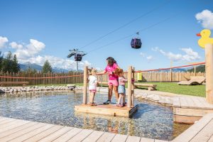Crianças brincando em uma jangada no lago do Giro d'Ali em Bellamonte, Val di Fiemme