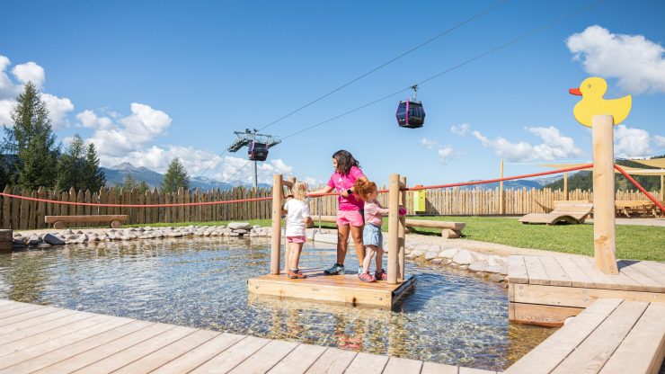 Crianças brincando em uma jangada no lago do Giro d'Ali em Bellamonte, Val di Fiemme