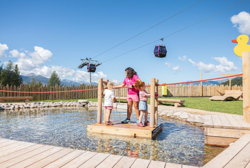 Crianças brincando em uma jangada no lago do Giro d'Ali em Bellamonte, Val di Fiemme